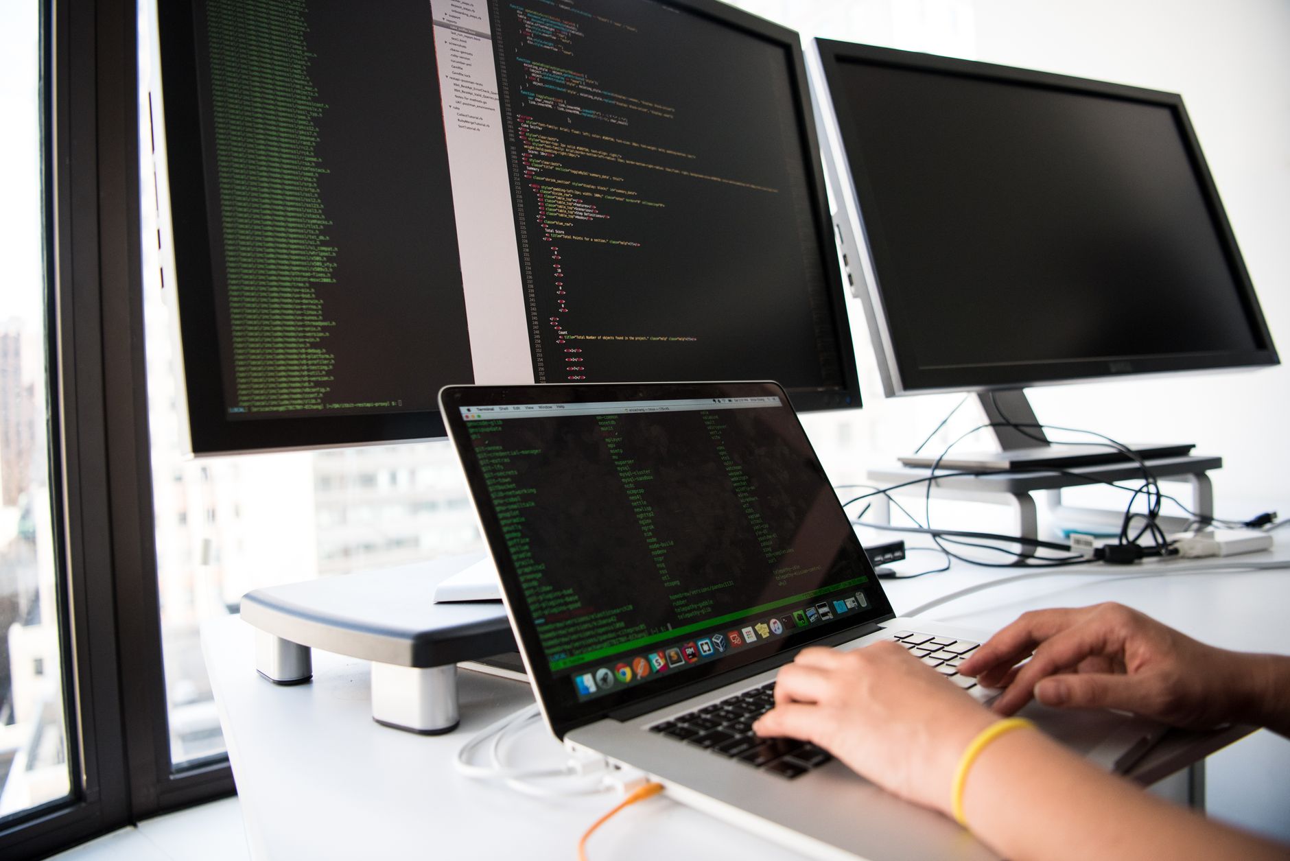 Programmer working across multiple monitors showing different types of coding frameworks in use